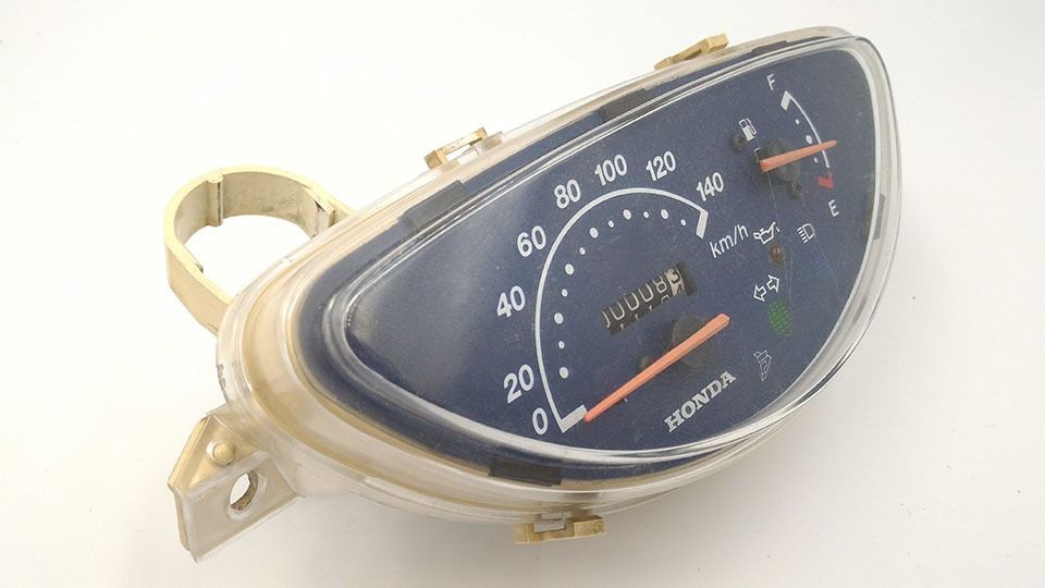 Un velocímetro Honda está sobre una superficie blanca.