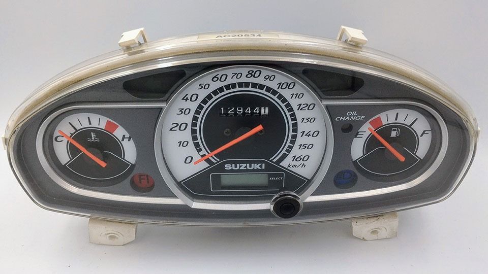 Un velocímetro de motocicleta Suzuki está sobre una superficie blanca.