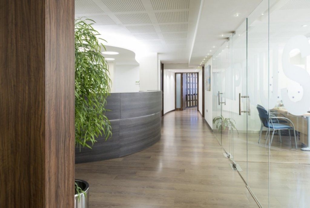 Un largo pasillo con una pared de cristal y un mostrador de recepción.