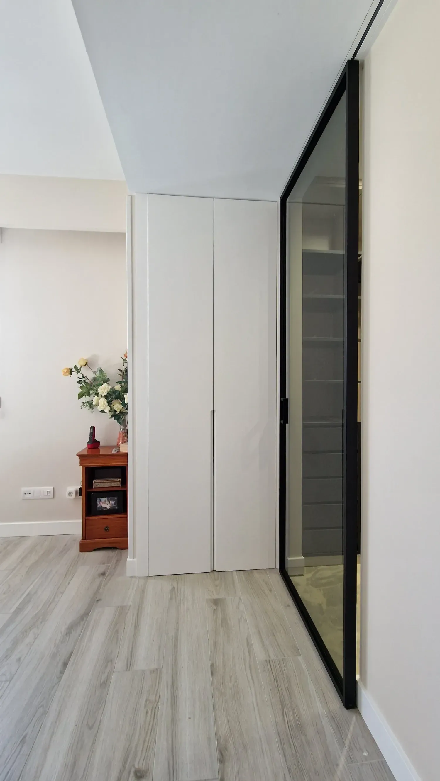 Un pasillo con armarios blancos y un espejo en la pared.