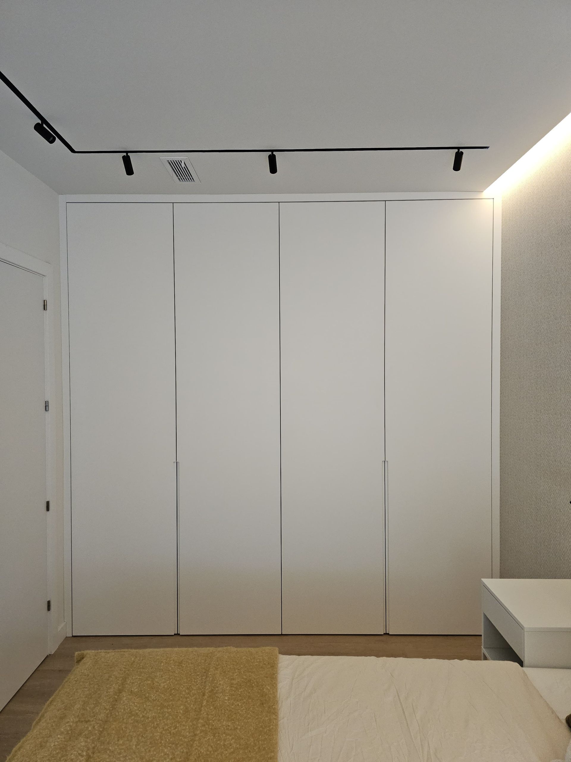 Un dormitorio con un gran armario blanco y una cama.