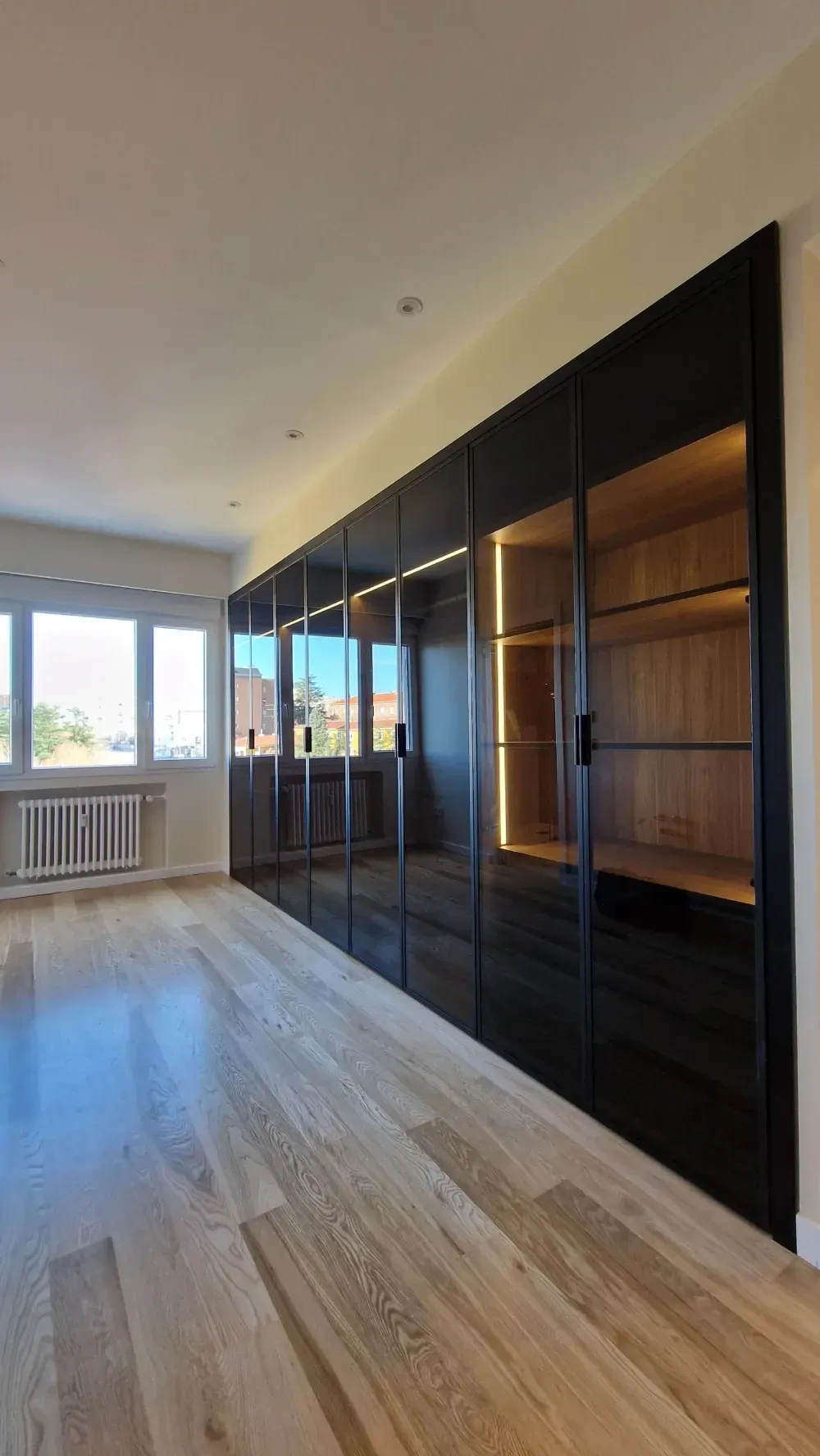 Una gran habitación vacía con pisos de madera y gabinetes negros.