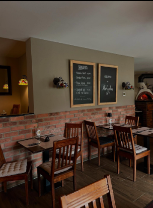 Restauranteinrichtung mit Holztischen, Stühlen, Ziegelwand und Menütafeln.