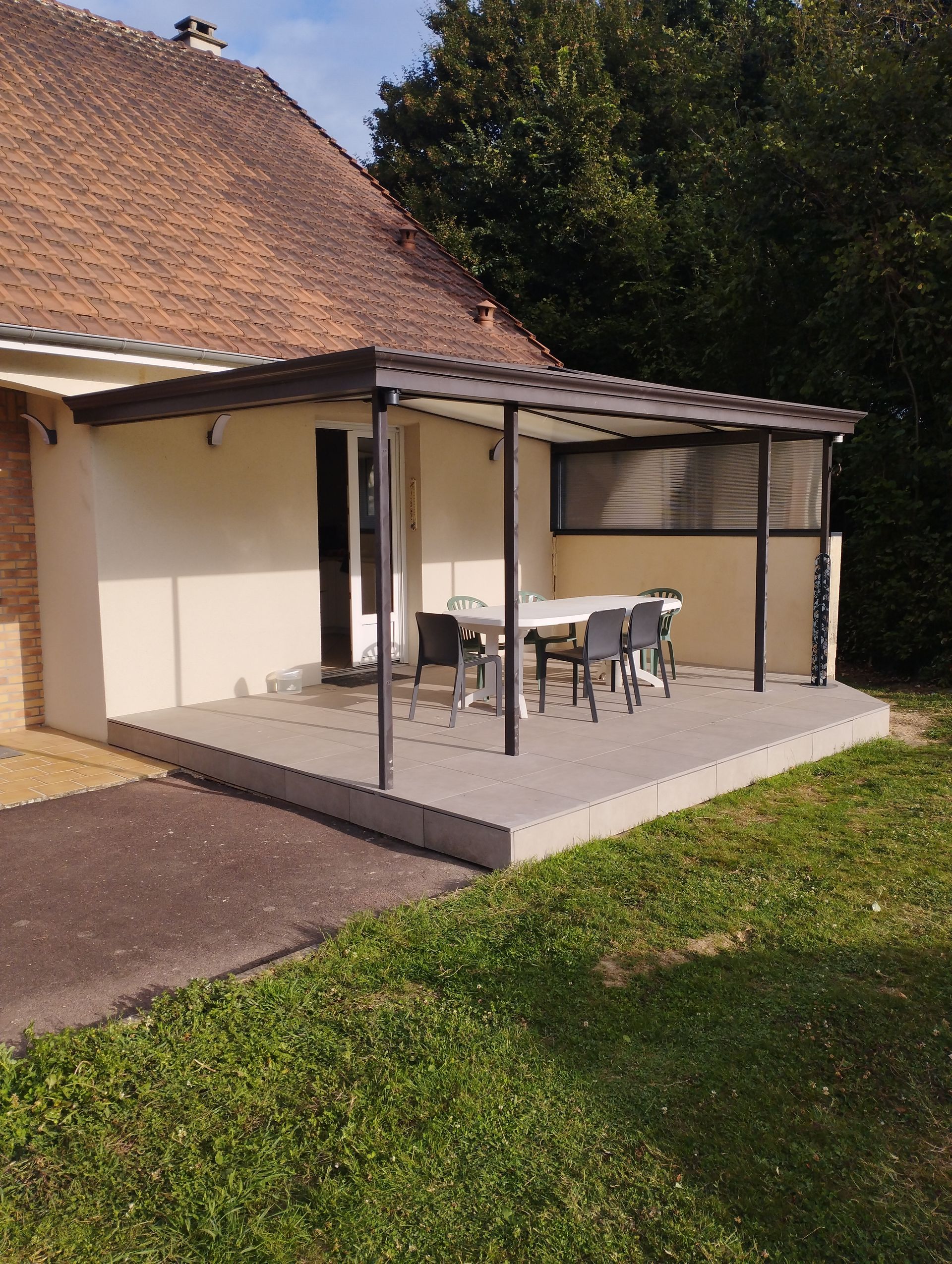 Une maison avec une terrasse surmontée d'une pergola et aménagée avec une table et des chaises