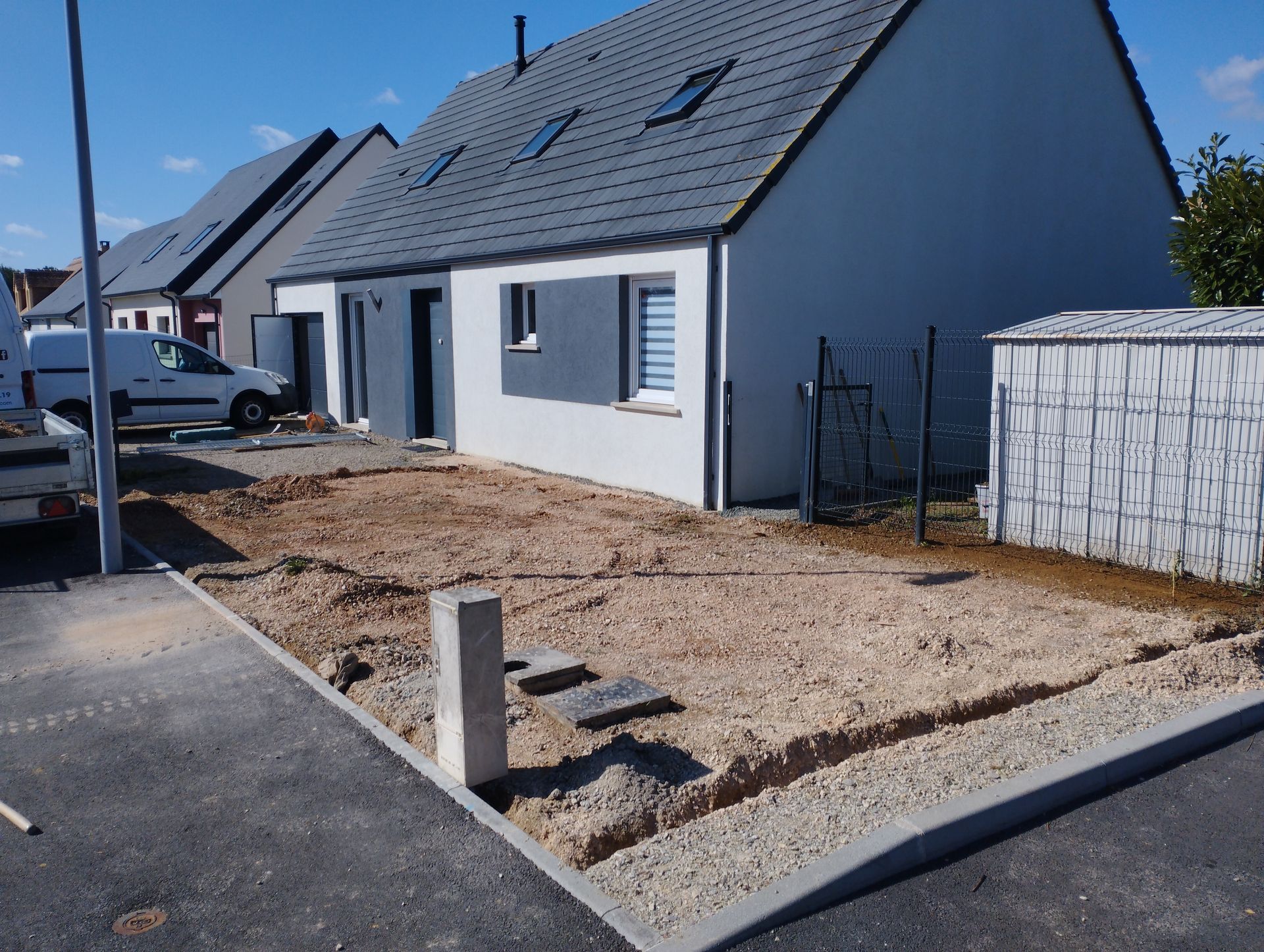 Une maison en construction avec une cour recouverte de terre et de gravier