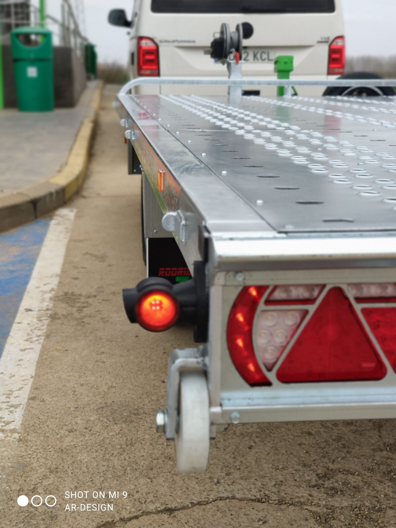 Primer plano de la parte trasera de un pequeño remolque plateado. Incluye una luz trasera roja