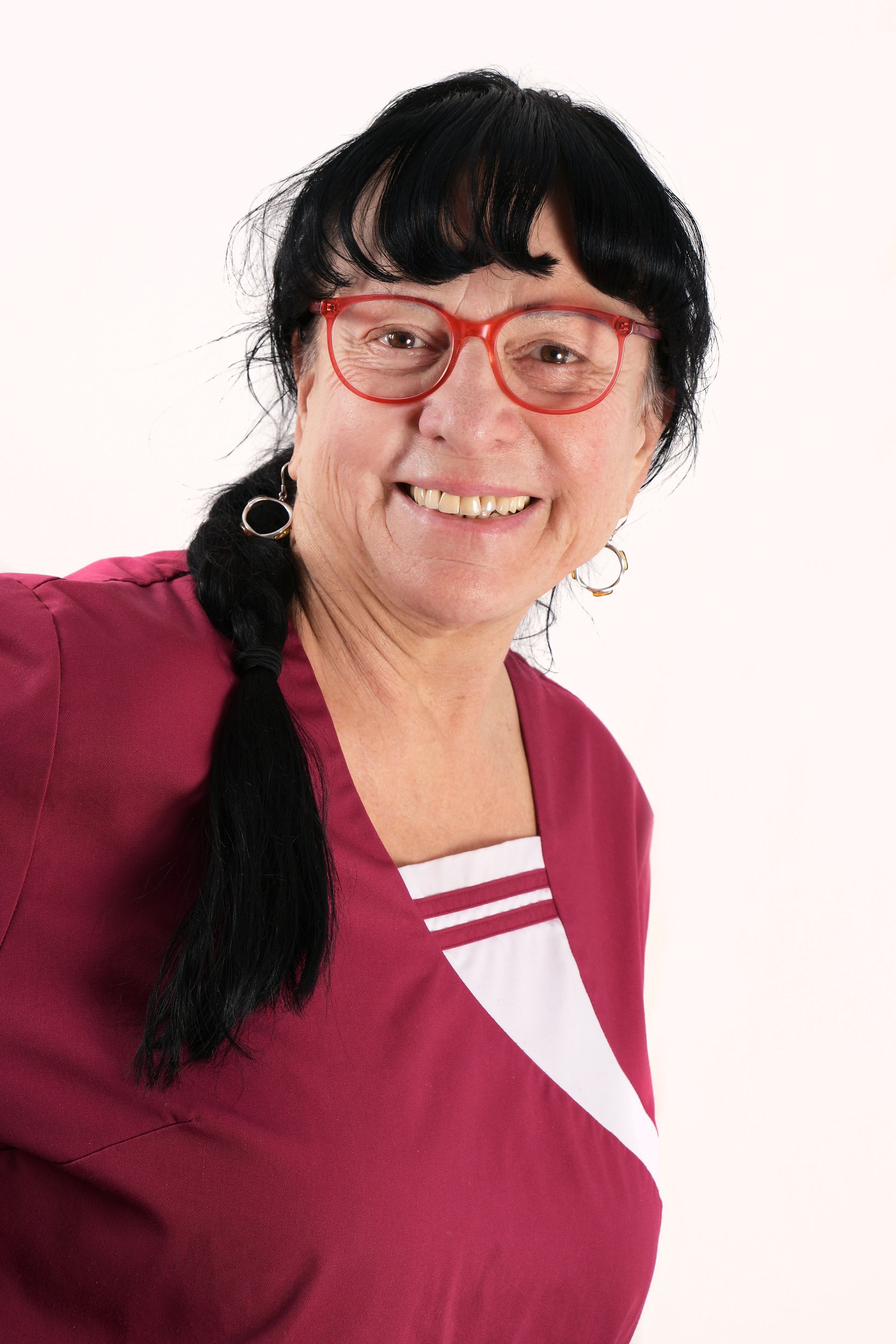 Porträt der Pflege- und Betreuungskraft Janna mit markanter roter Brille und dunklem Pony.