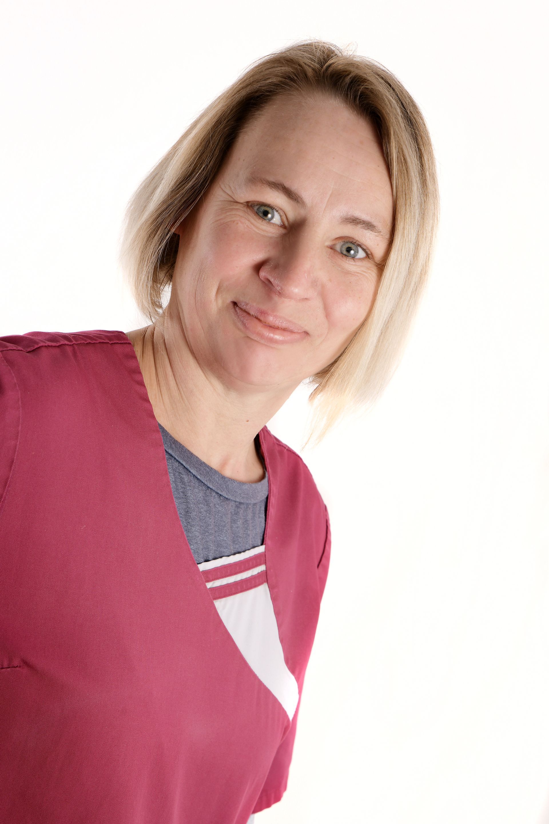Porträt der Pflegekraft Janina mit blondem, kinnlangem Haar und einem sympathischen Lächeln.