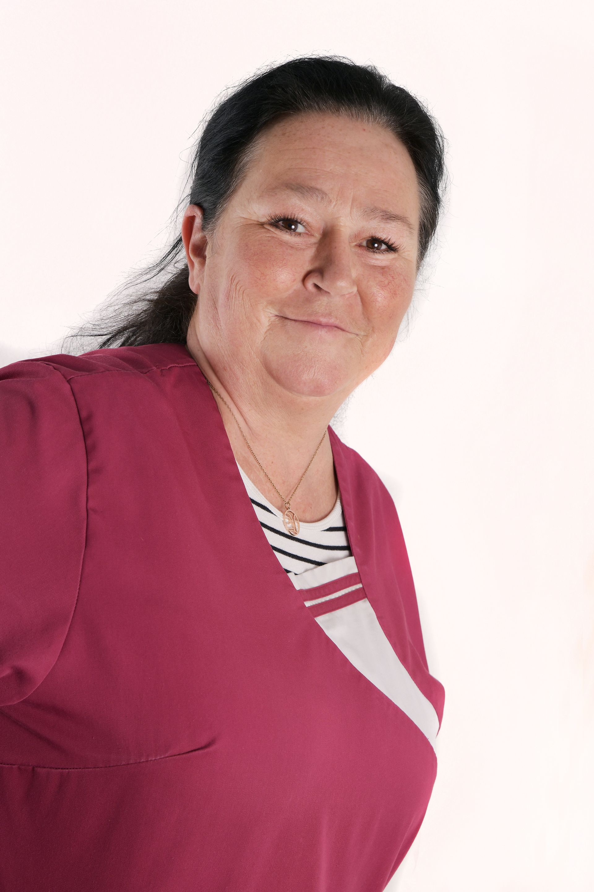 Porträt der Pflegekraft Yvonne mit dunklem Haar und einem freundlichen Gesichtsausdruck.