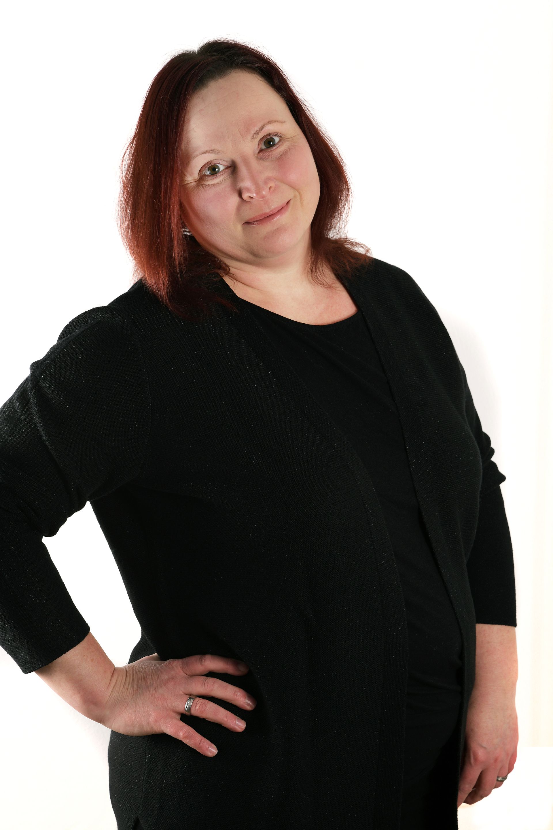 Portrait von Manuela, der Verwaltungsfachkraft, mit mittellangen, leicht rötlichen Haaren und einem ruhigen Gesichtsausdruck.
