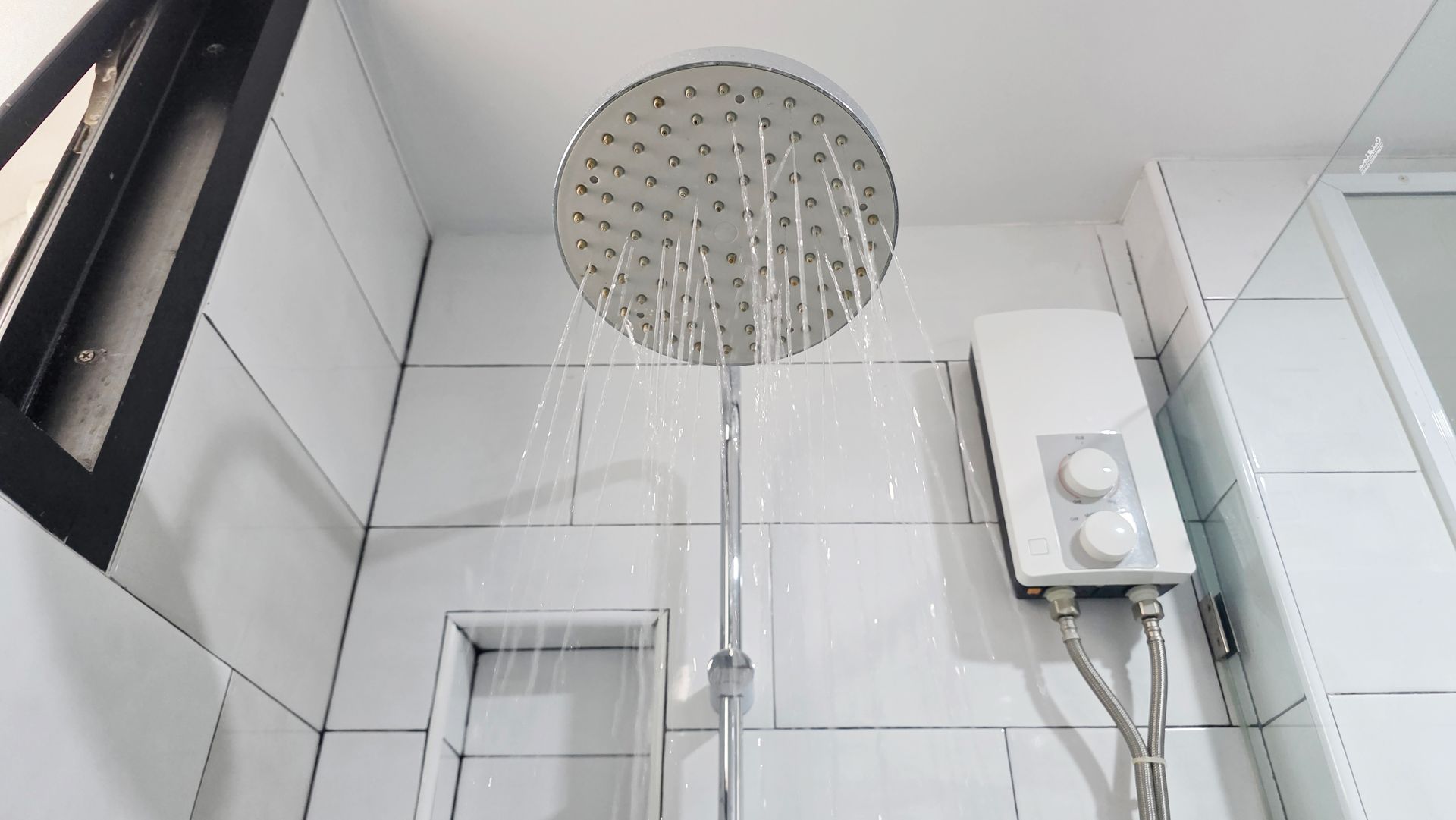Un chauffe-eau mural installé directement dans une douche, à côté du pommeau.