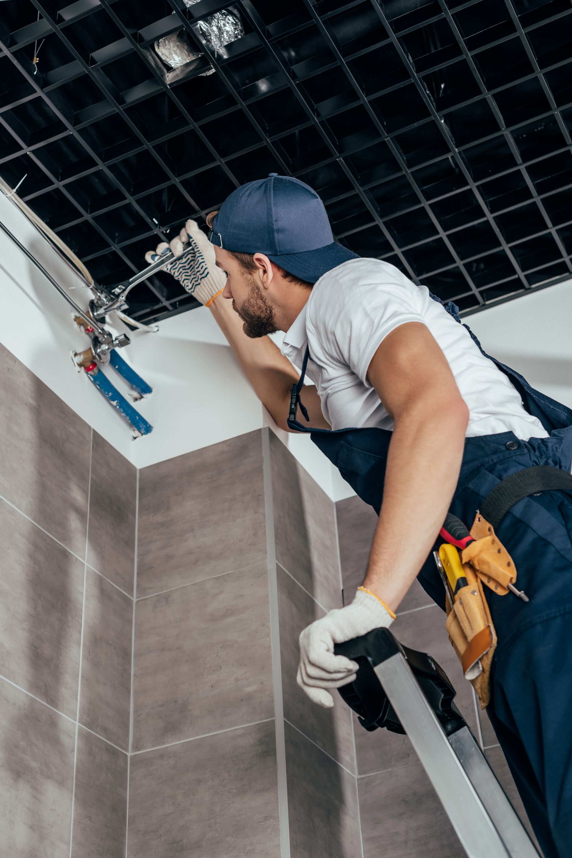 Un plombier réalise des travaux dans une salle de bains.