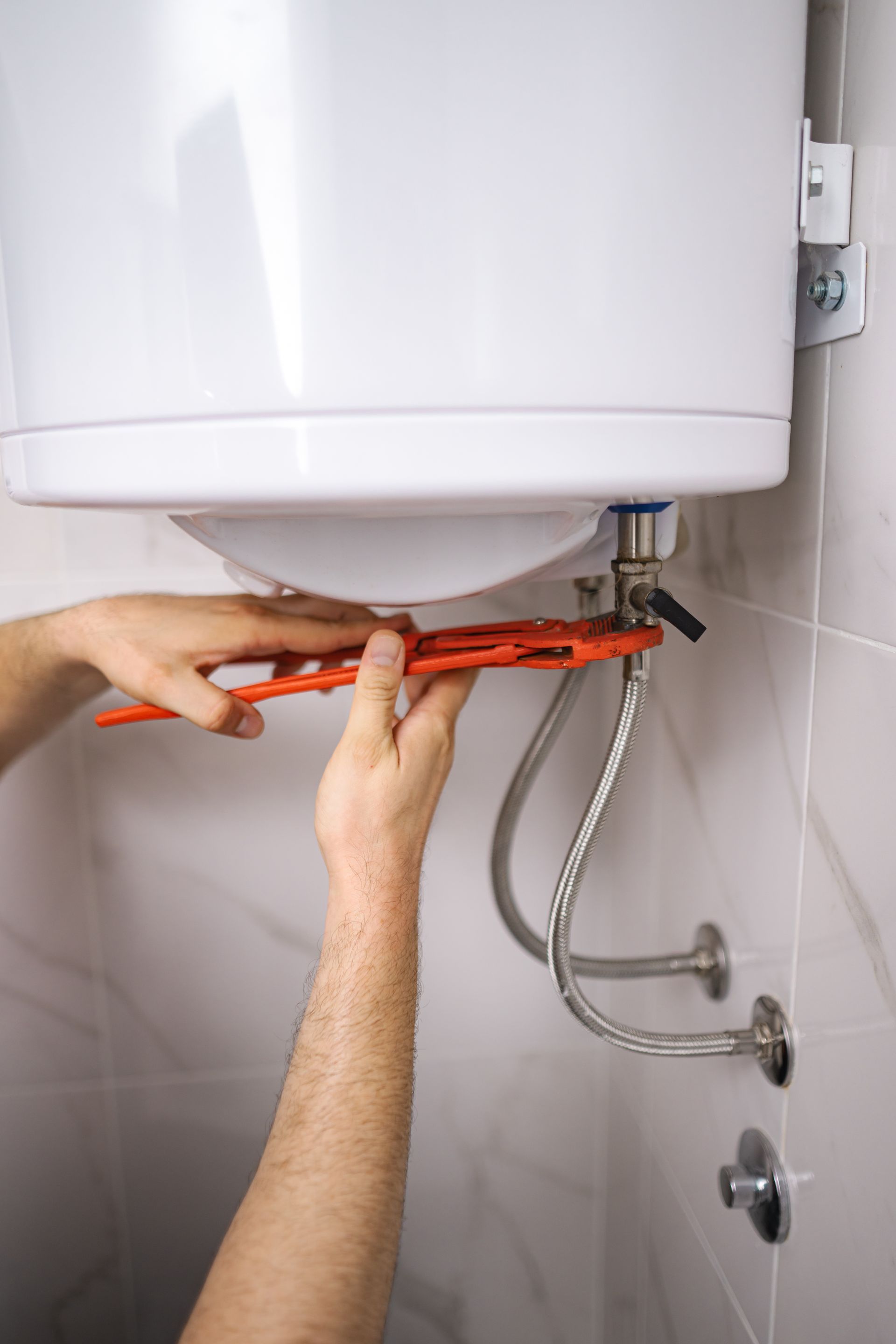 Un plombier réalise la maintenance d'un chauffe-eau.