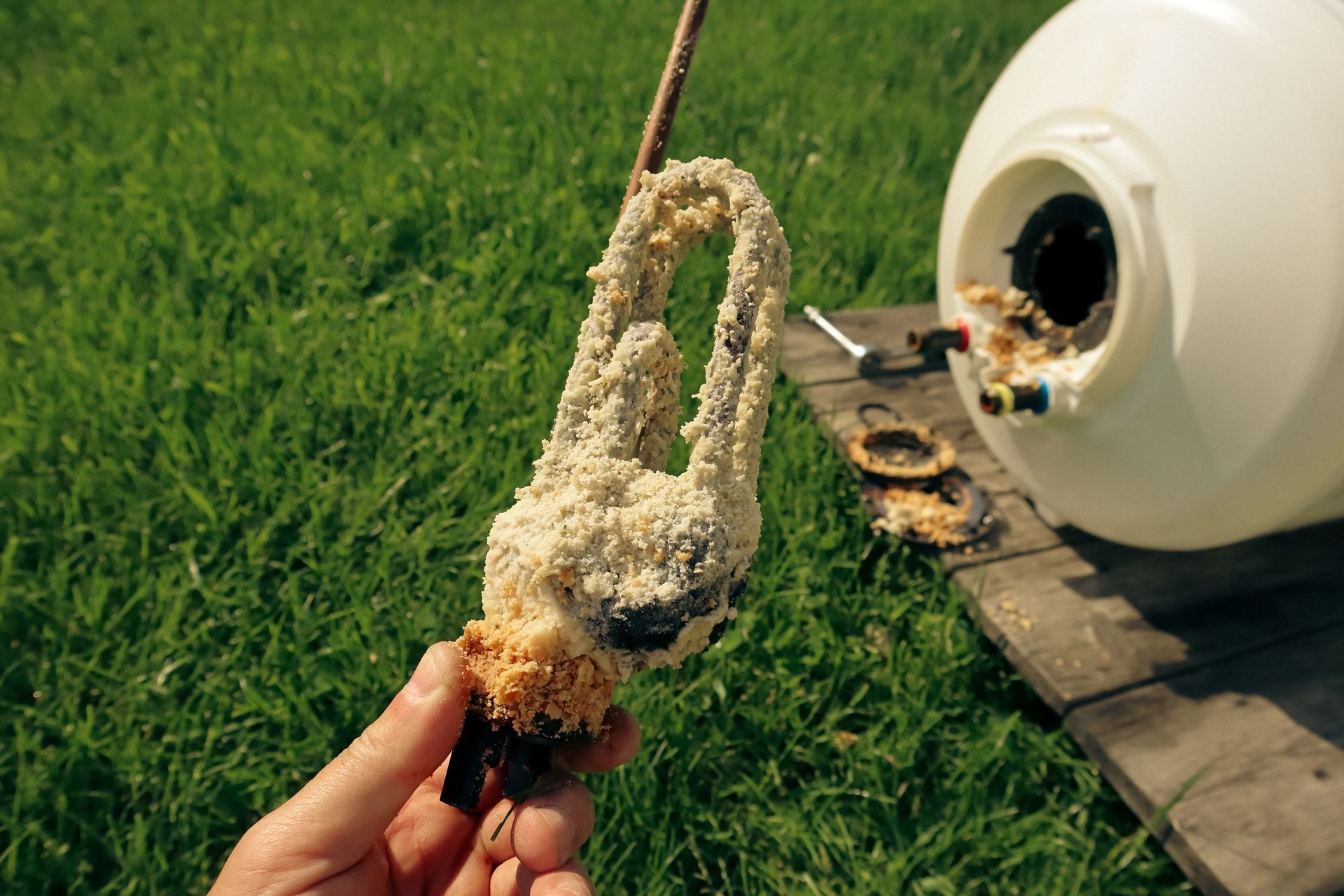 Une main tenant des dépôts de calcaire provenant d'un chauffe-eau électrique domestique.