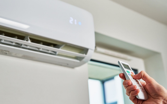 Une personne règle la température d'un climatiseur avec une télécommande.