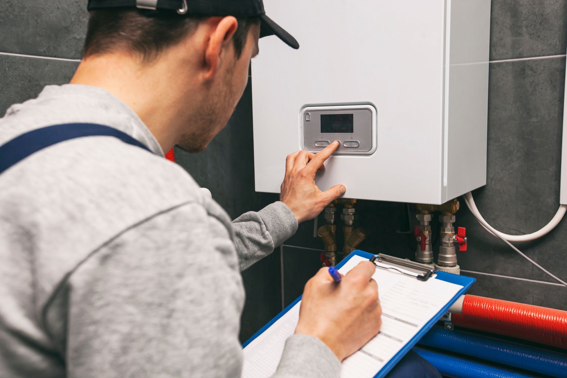 Un technicien inspecte un chauffe-eau mural et prend des notes sur un bloc-notes.