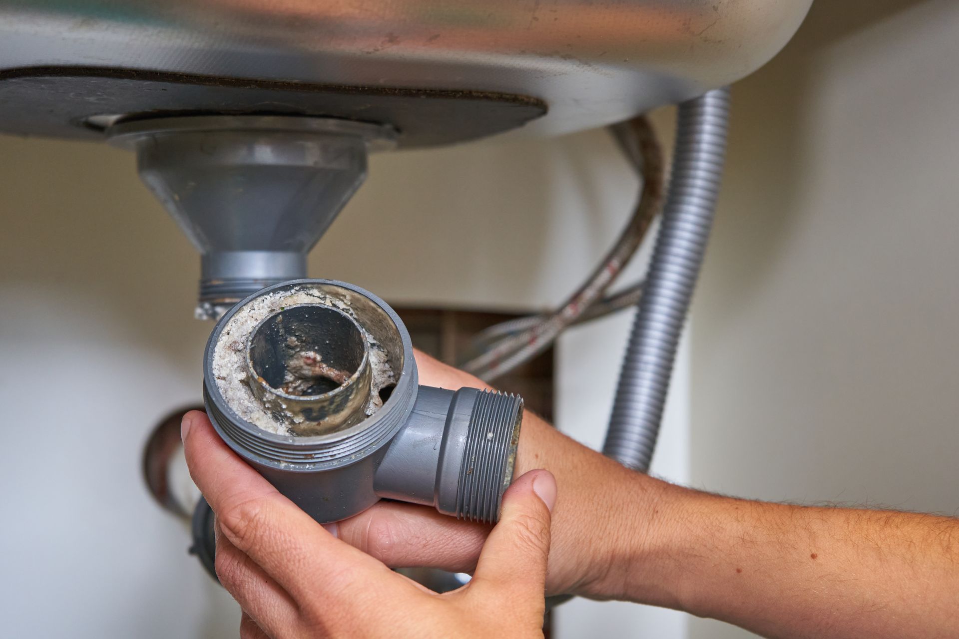 Un plombier nettoie le siphon bouché d'un évier de cuisine.