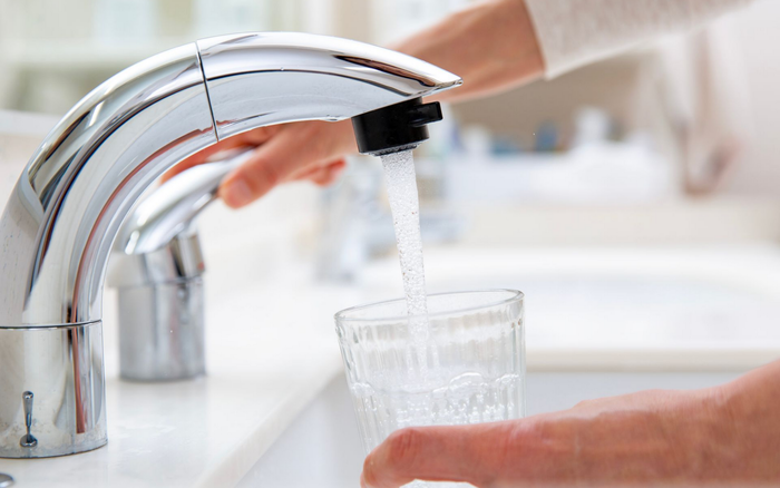 Une personne remplit un verre d'eau du robinet.