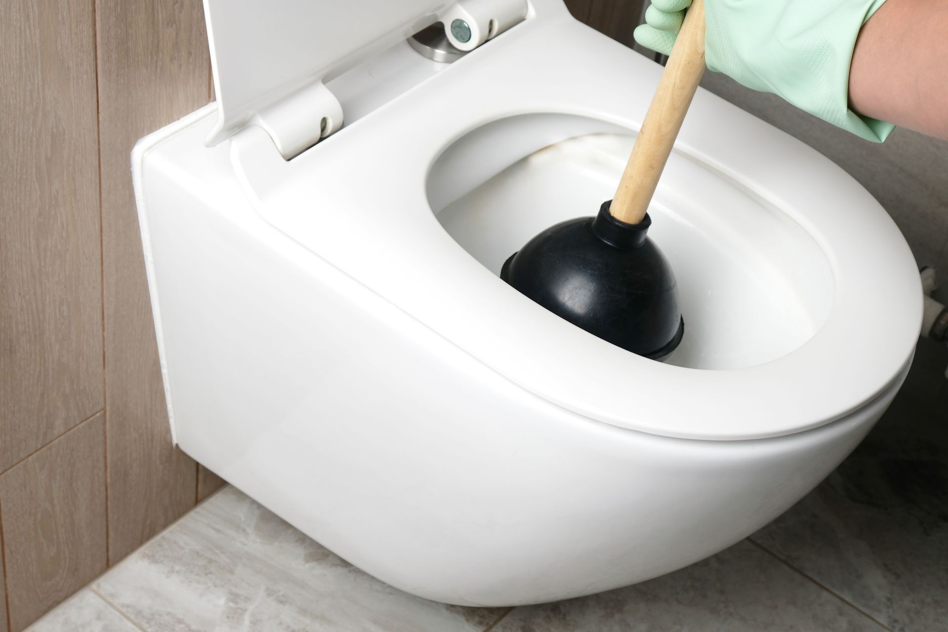 Une personne débouche des toilettes avec une ventouse.