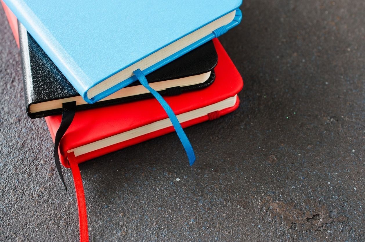 Tres cuadernos están apilados uno encima del otro sobre una mesa.