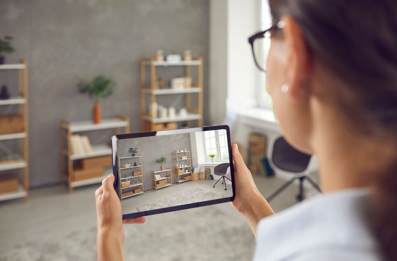 Mujer sosteniendo una tableta, usando realidad aumentada para visualizar la ubicación de los muebles en una habitación.