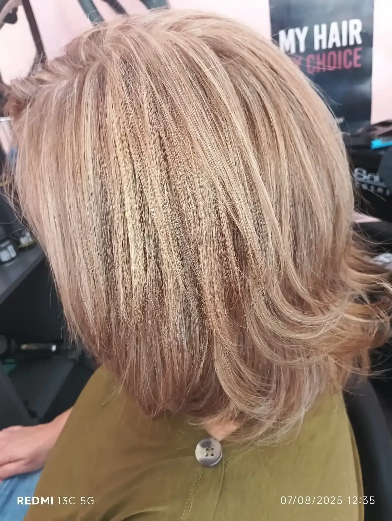 Persona con cabello rubio largo y ondulado que lleva una chaqueta vaquera azul.