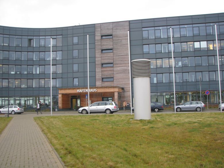 Ein großes Gebäude mit vielen Fenstern und davor geparkten Autos