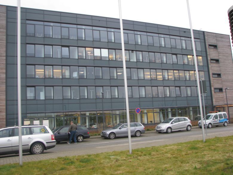 Ein Gebäude mit vielen Fenstern und davor geparkten Autos