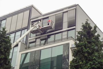 Ein Kran reinigt die Fenster eines großen Gebäudes.