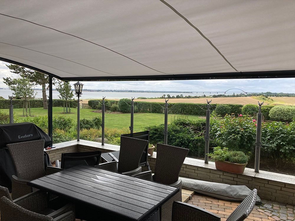 Eine Terrasse mit Tisch und Stühlen und Blick auf ein Feld.