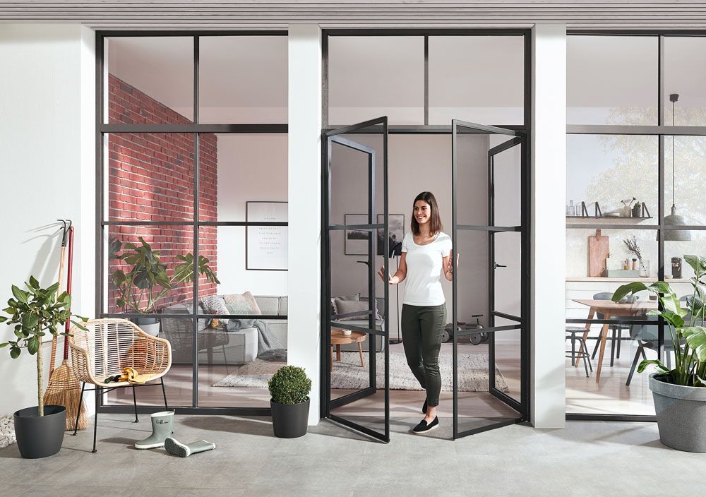 Eine Frau steht vor einer Glastür in einem Wohnzimmer.