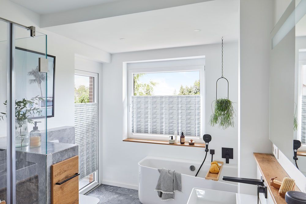 Ein Badezimmer mit Badewanne, Waschbecken, Spiegel und Fenster.