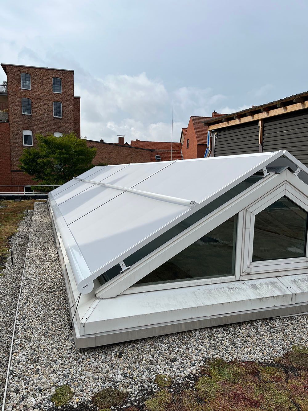 Auf einem mit Kies bedeckten Dach sitzt ein weißes Dach mit vielen Fenstern.