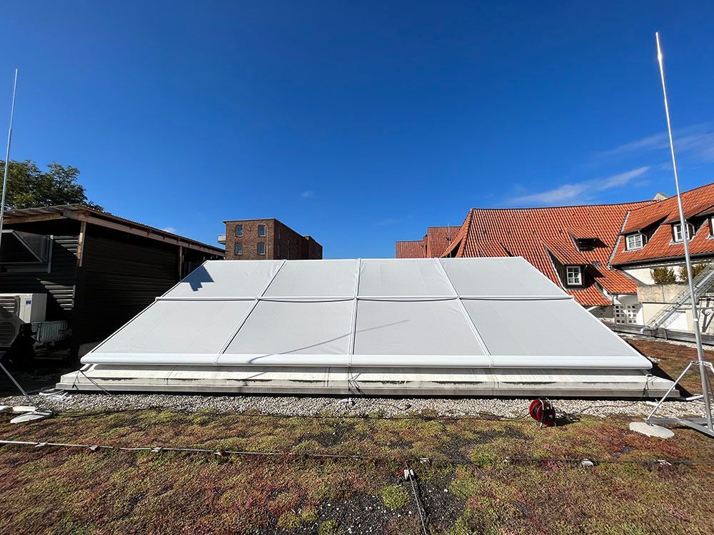 Auf einem grünen Dach steht ein großes weißes Zelt.