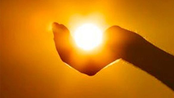 Una mano que acaricia el brillante sol contra un cielo anaranjado.
