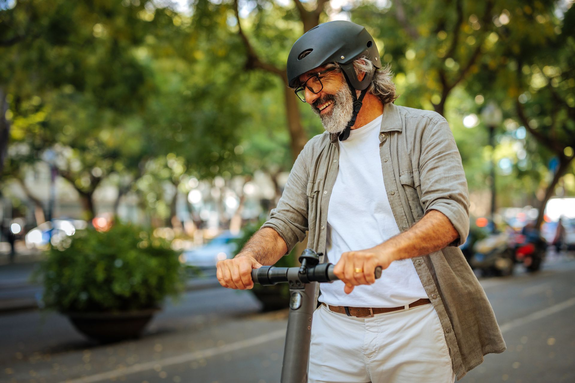 Homme à la barbe blanche souriant sur une trottinette