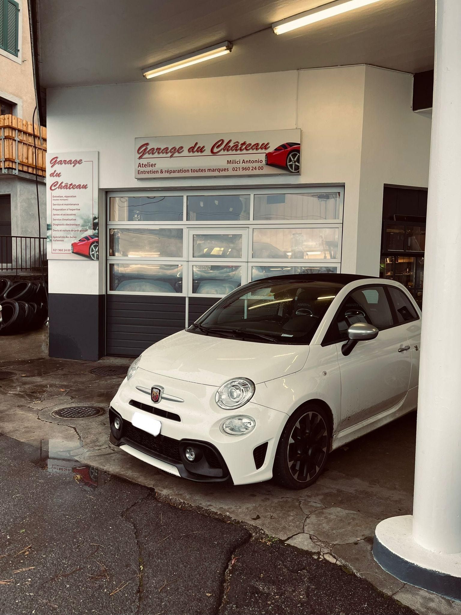 Un homme travaille sur le dessous d'une voiture dans un garage.