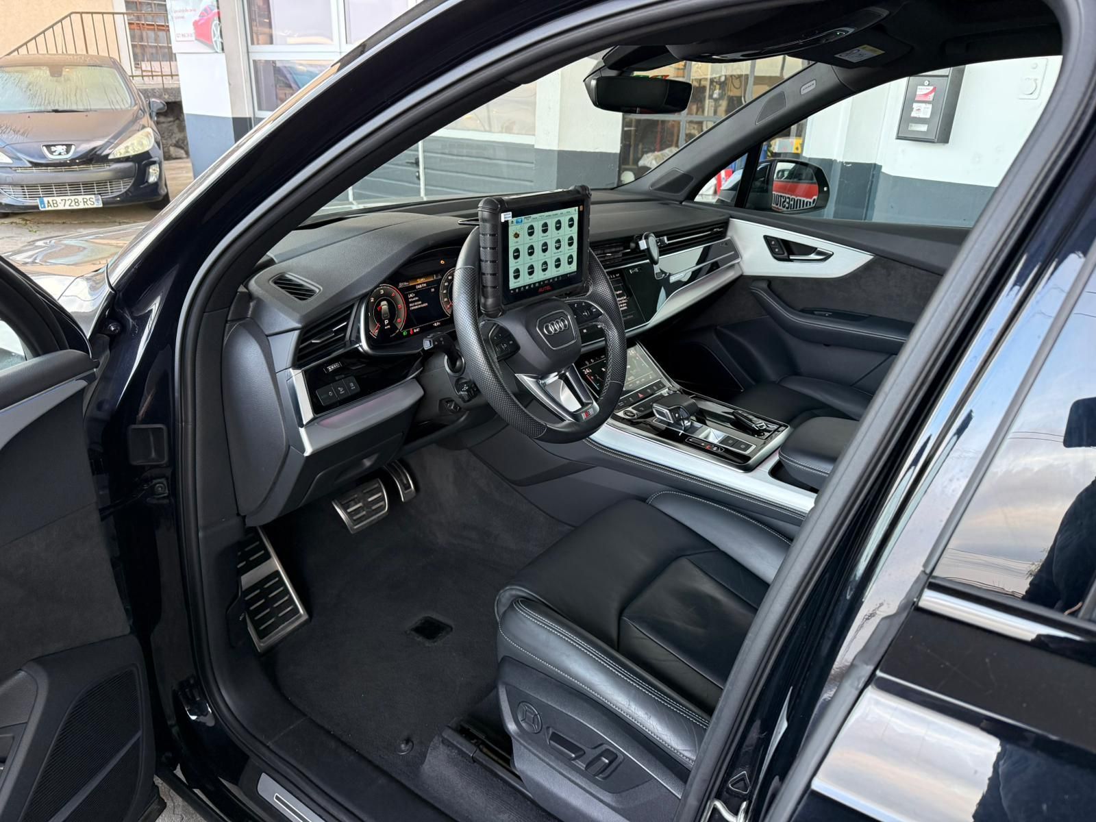 Voiture de sport grise Mercedes-AMG GT garée dans une rue, à proximité d'autres voitures et d'un bâtiment.