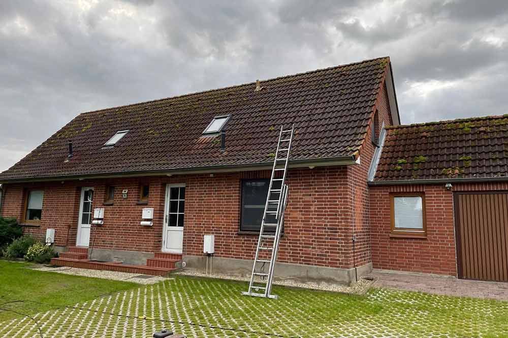 Ein Backsteinhaus mit braunem Dach und weißen Fenstern