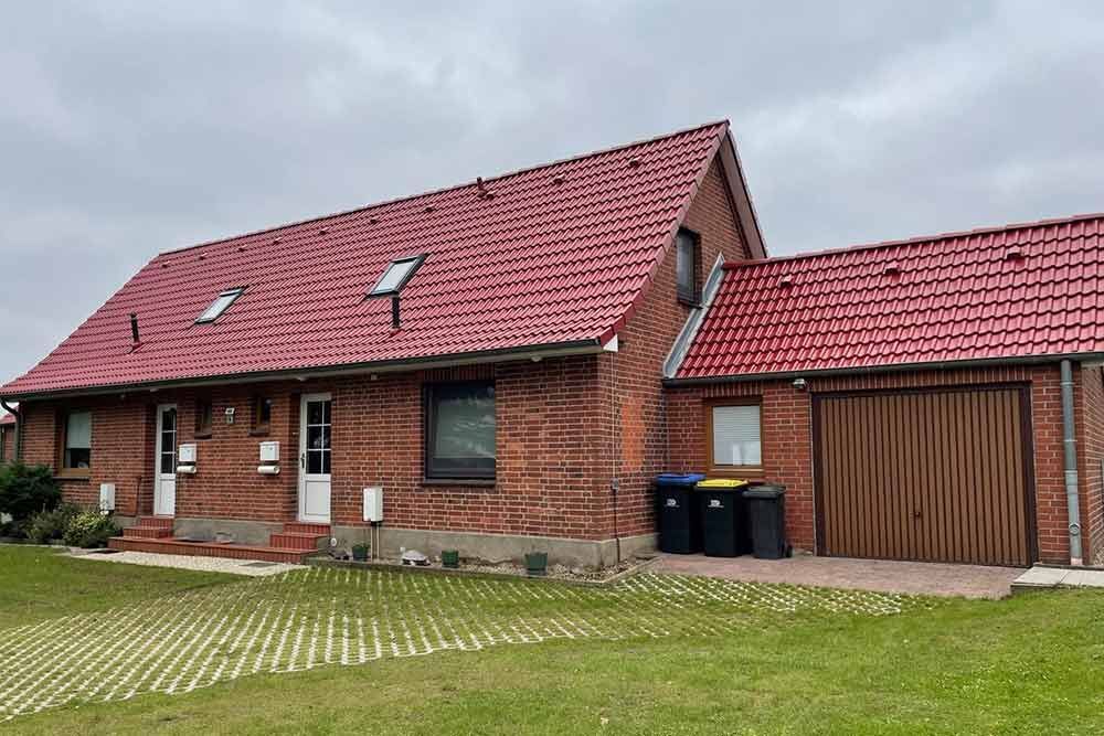 Ein Backsteinhaus mit schwarzem Dach und weißen Fenstern