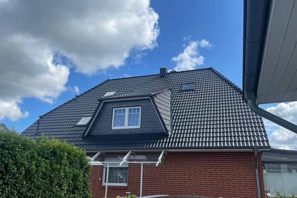 Ein Backsteinhaus mit einem schwarzen Dach und einem Fenster.