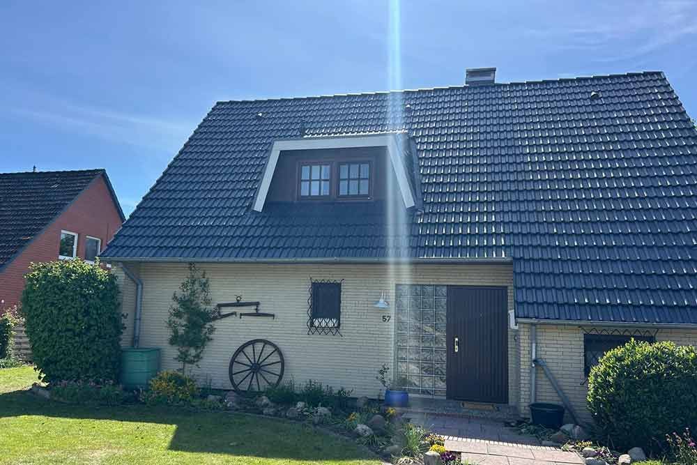 Ein Haus mit blauem Dach und einem Wagenrad davor