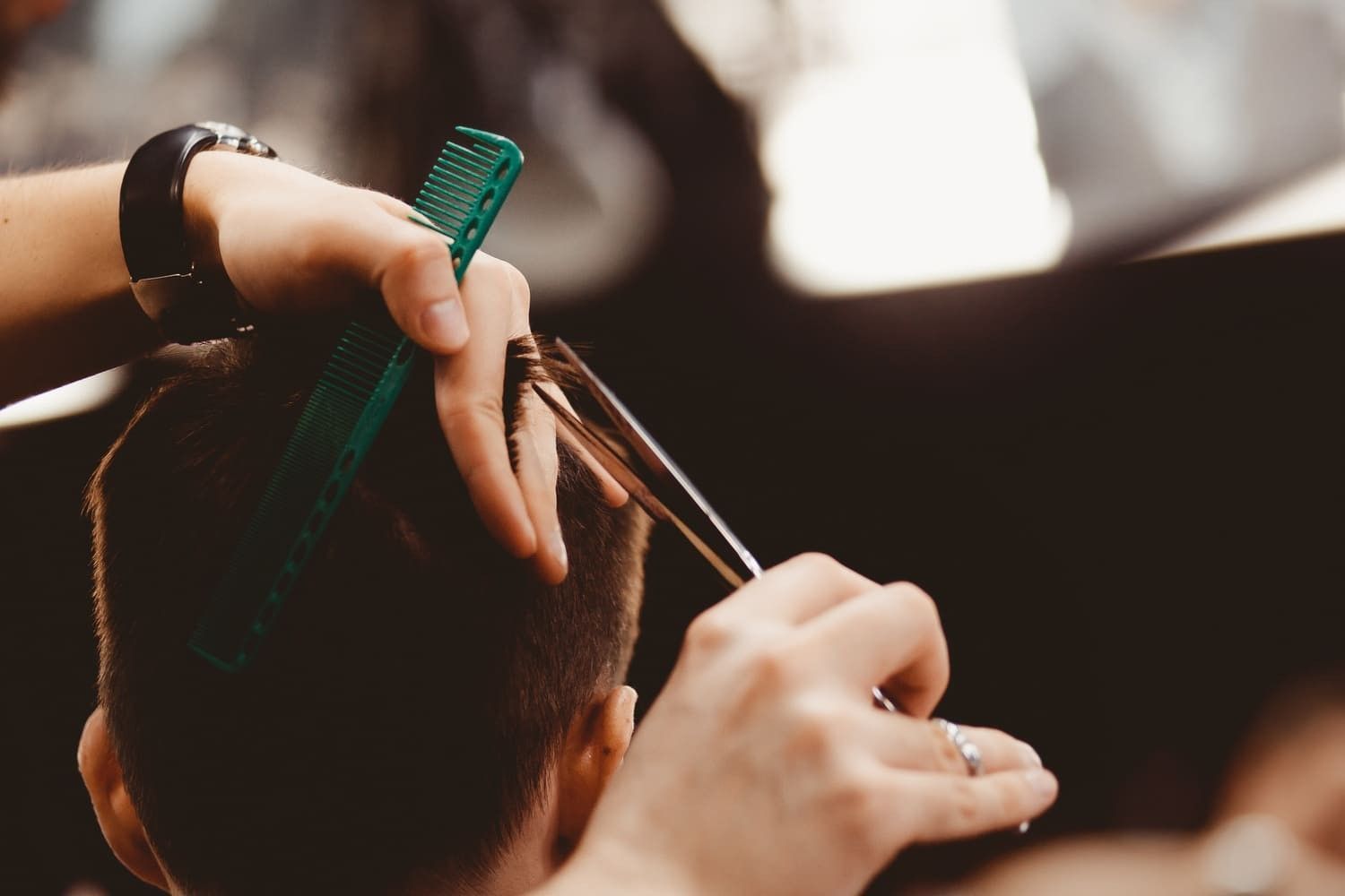 Barbero usando tijeras para cortar el cabello de un cliente con un peine, toma de primer plano.