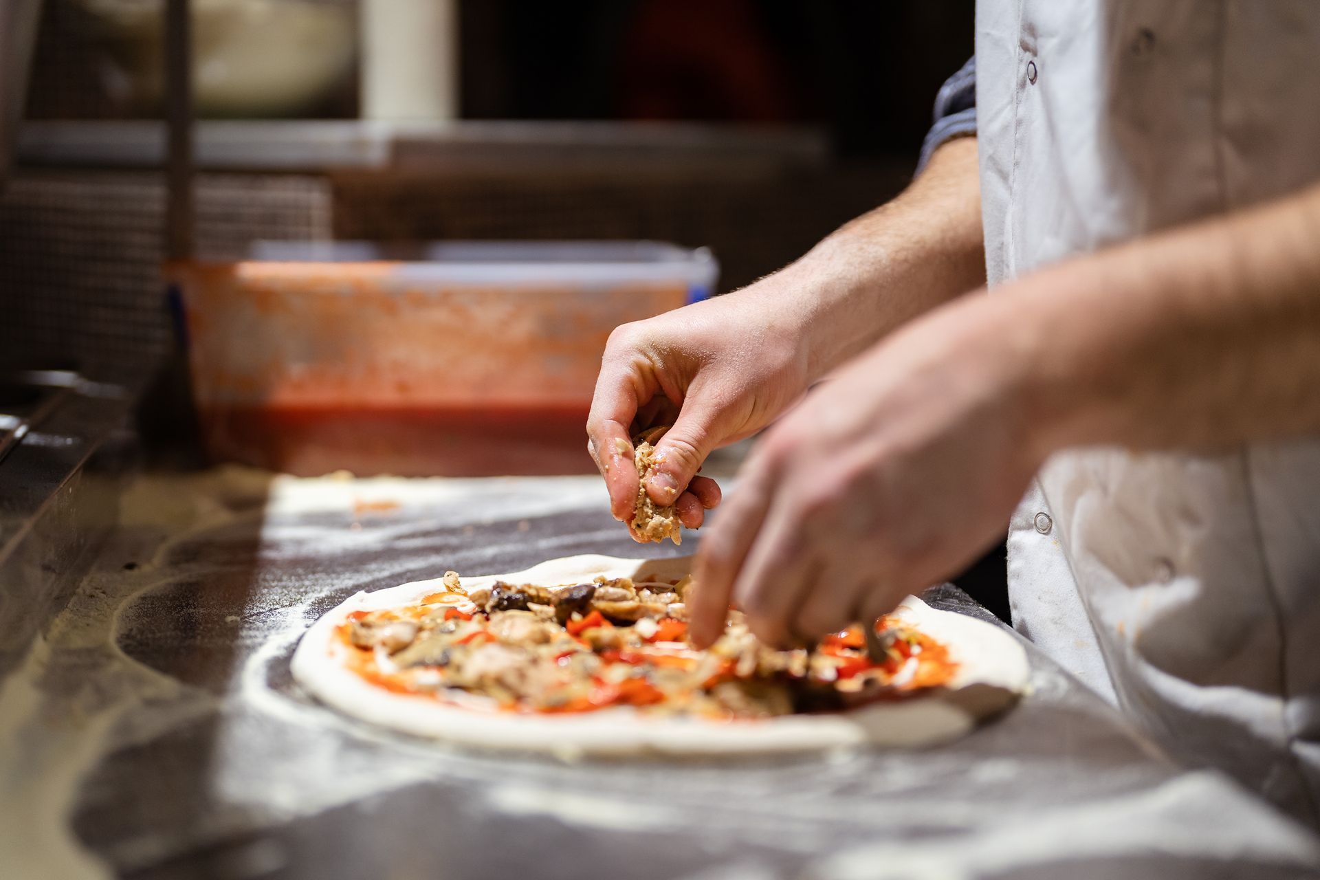 Un chef ajoute des garnitures à une pizza dans la cuisine d'un restaurant.