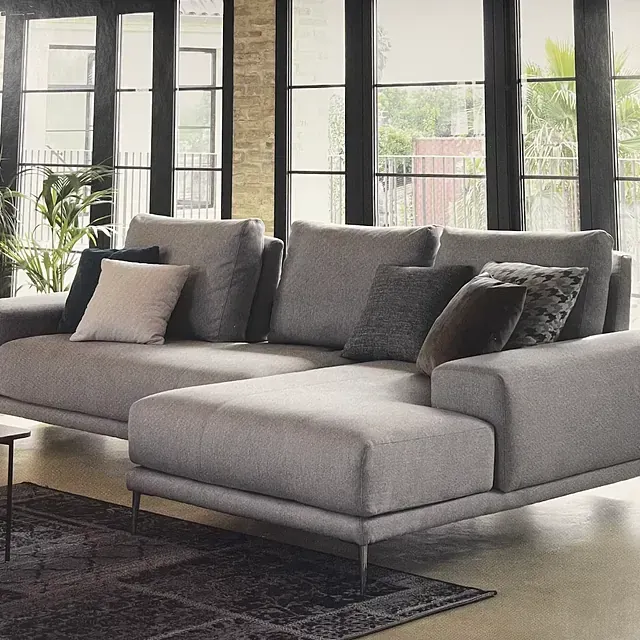 Una sala de estar con un gran sofá seccional y muchas ventanas.