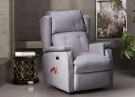 Un sillón reclinable gris se encuentra en una sala de estar al lado de una mesa pequeña.