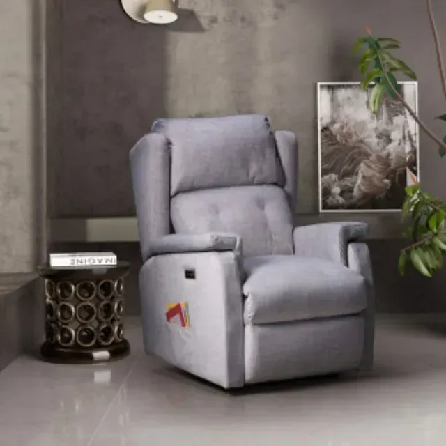 Un sillón reclinable gris en una sala de estar junto a una mesa.