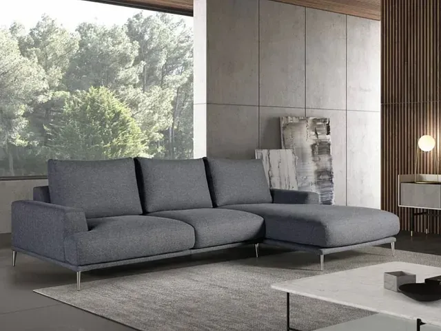 Una sala de estar con un sofá seccional gris y una mesa de café blanca.