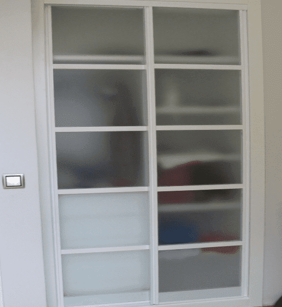 Un armario con puertas corredizas de vidrio y estantes en una habitación.