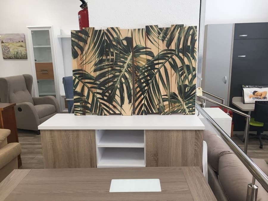 Una sala de estar con un cuadro de hojas de palma en la pared.